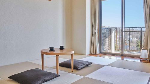 a living room with a table and a large window at Tokyu Vacations Izukougen in Ito