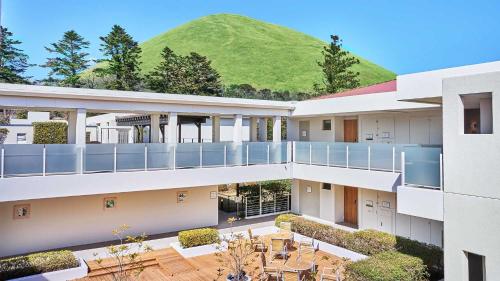 a building with a green hill in the background at Tokyu Vacations Izukougen in Ito