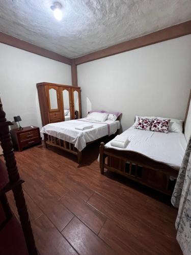 a bedroom with two beds and a wooden floor at Ibania Hostal in Tamanique