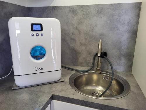 - un lave-linge à côté d'un évier dans la cuisine dans l'établissement Charmant Chalet 2 Chambres avec Terrasse à 100m du Lac de Jouarres, Piscine Chauffée, Climatisation - FR-1-783-8, à Olonzac