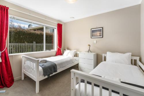 two beds in a bedroom with a window at Kinloch Hideaway - Taupo in Kinloch