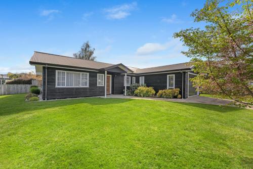a house with a green lawn in front of it at Kinloch Hideaway - Taupo in Kinloch