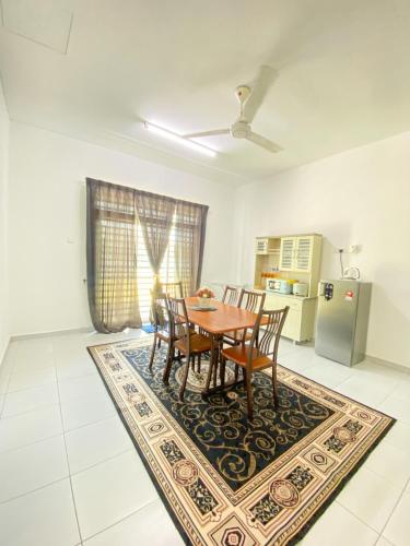 a dining room with a table and chairs on a rug at Dramayu Homestay in Cukai