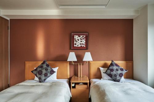two beds in a room with brown walls at Tokyu Vacations Kyoto in Kyoto