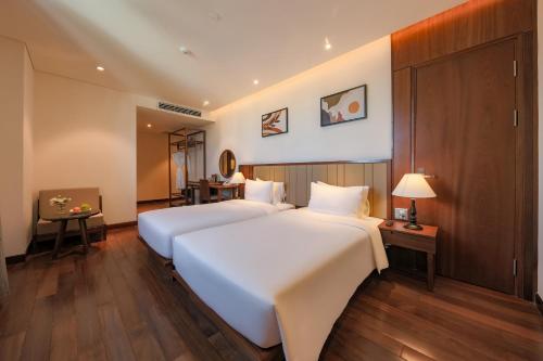 a hotel room with two beds and a desk at Green Beach Hotel Nha Trang in Nha Trang