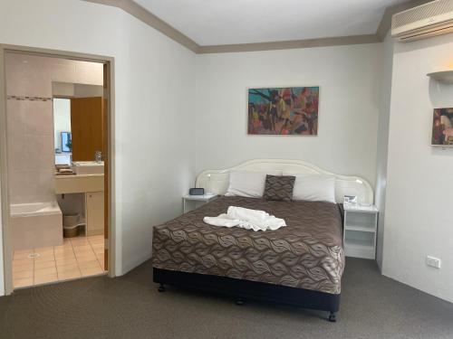 a bedroom with a bed and a bathroom at Oasis Inn Ulladulla - Welcoming Guests 18 Years and Older in Ulladulla