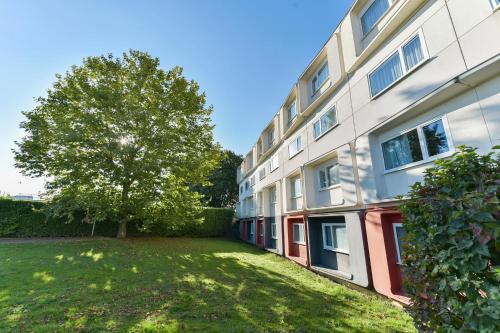 an apartment building with a tree in the yard at Golden Tulip Roissy Saint Witz in Saint-Witz