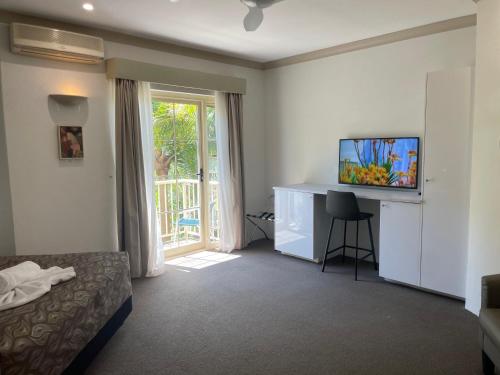 a hotel room with a bed and a desk with a television at Oasis Inn Ulladulla - Welcoming Guests 18 Years and Older in Ulladulla