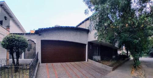a house with a large garage with a fence at Habitación 2 en Casa Retro in Medellín