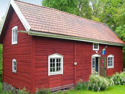 a red barn with white windows and a roof at Awesome Home In Vimmerby With 2 Bedrooms, Wifi And Sauna in Vimmerby