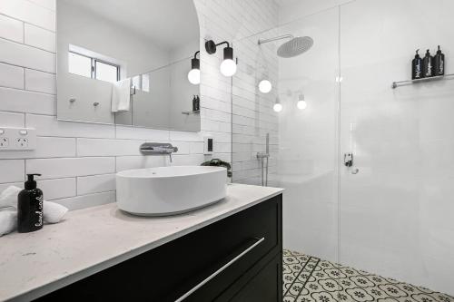 a white bathroom with a sink and a shower at Gardiner Cottage - Stylish & Elegant, Walk to CBD in Orange