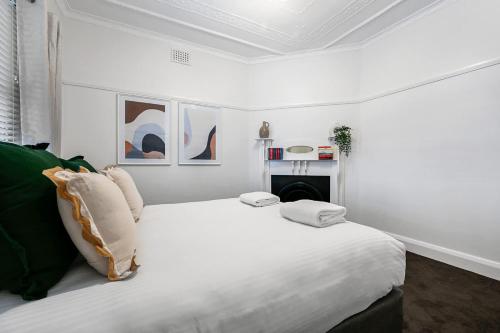 a white bedroom with a large bed and a fireplace at Gardiner Cottage - Stylish & Elegant, Walk to CBD in Orange