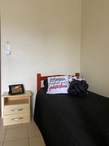 a bedroom with a bed and a wooden night stand at Pousada Nova in Tramandaí