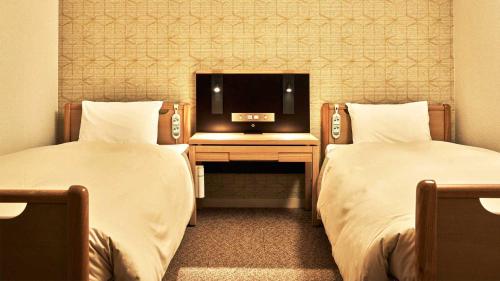 two beds in a room with a tv on a desk at Tokyu Vacations Hakone Gora in Hakone