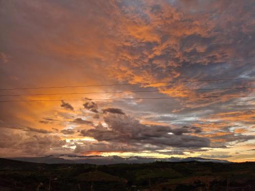 a cloudy sky at sunset with mountains in the background at Tacuara House in San Gil