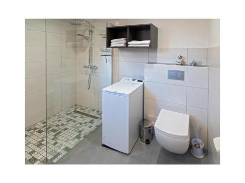 a white bathroom with a toilet and a shower at Holiday apartment Möwenblick in Norden