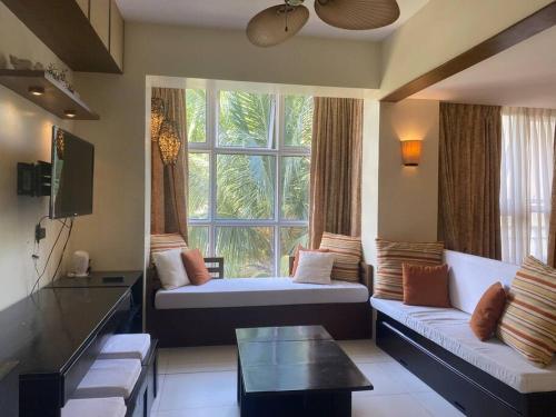 a living room with two beds and a window at Carola Pico De Loro in Nasugbu