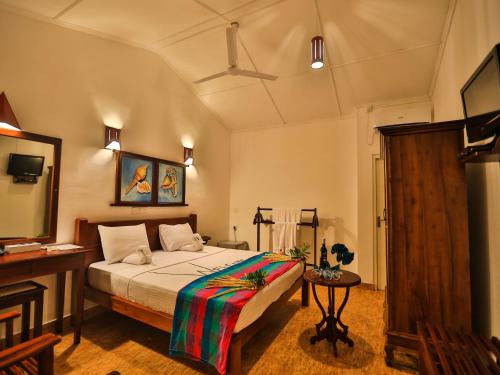a bedroom with a bed and a table in a room at Thejan Beach Cabanas in Bentota