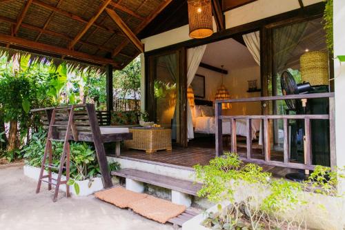a porch of a resort with a bed and a table at Mantaray Siargao in General Luna