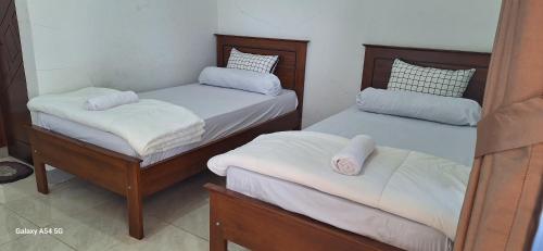 une chambre avec deux lits avec des draps blancs dans l'établissement ABC Guest House Labuan Bajo, à Labuan Bajo