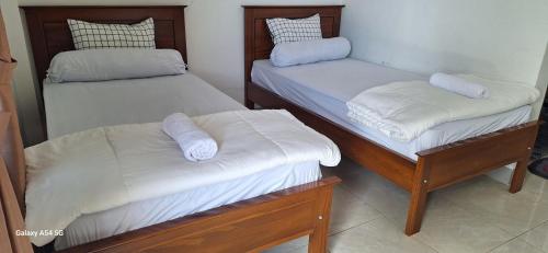 Cette chambre comprend 2 lits avec des draps et des oreillers blancs. dans l'établissement ABC Guest House Labuan Bajo, à Labuan Bajo