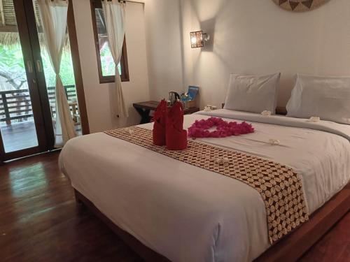 un dormitorio con una cama grande con zapatos rojos encima. en Gili Air Santay Bungalows, en Gili Air