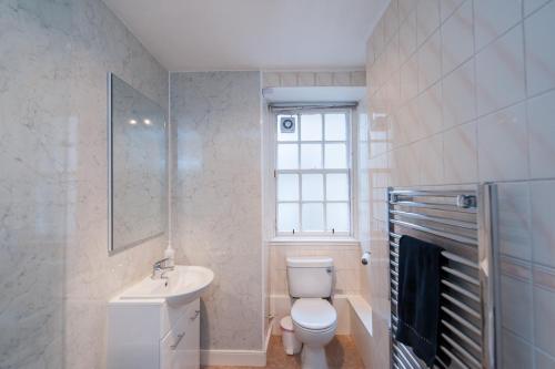 a bathroom with a toilet and a sink and a window at Writers View, Royal Mile Apartment Edinburgh in Edinburgh