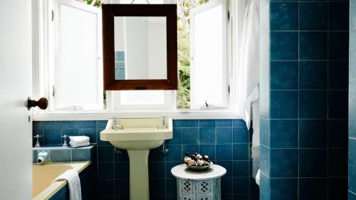 a blue tiled bathroom with a sink and a mirror at Rockridge in Palm Beach