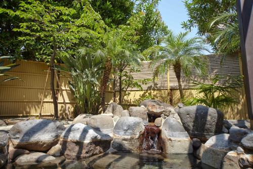 a pond with rocks and a fountain in a yard at Tokyu Vacations Izuimaihama in Kawazu