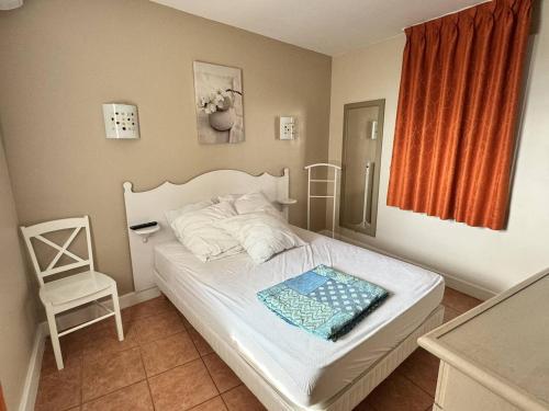 une chambre avec un lit blanc et une chaise dans l'établissement Appartement climatisé avec piscine et animaux admis - FR-1-768-104, à Roquebrune-sur Argens