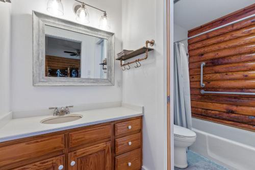 a bathroom with a sink and a toilet and a mirror at Guadalupe Bluff Log Cabin in Kerrville