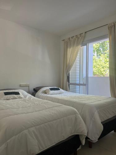 two beds in a bedroom with a window at 25 de Mayo Apartment in Estación Libertador General San Martín