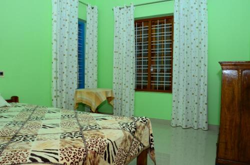 a bedroom with a bed and a window at Vaiga Home Stay in Kovalam