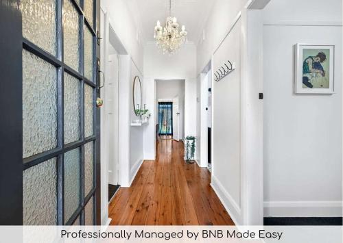 a hallway with wood floors and a chandelier at Gardiner Cottage - Stylish & Elegant, Walk to CBD in Orange