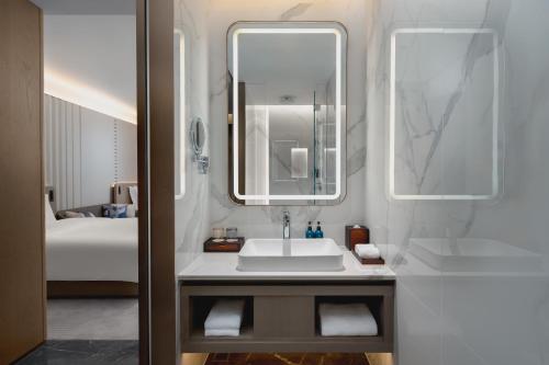 a bathroom with a sink and a mirror and a bed at Crowne Plaza Kunshan East by IHG in Kunshan
