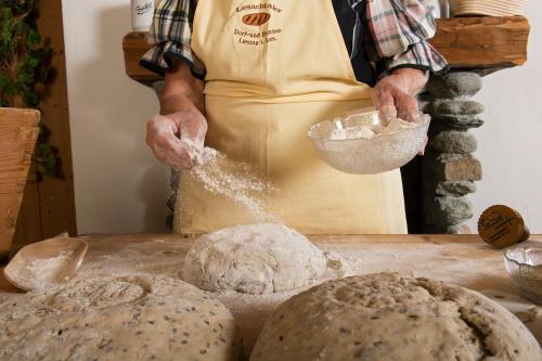 a person in an apron making bread on a table at Alpenhotel Wanderniki in Liesing