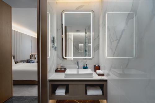 a bathroom with a sink and a mirror and a bed at Crowne Plaza Kunshan East by IHG in Kunshan