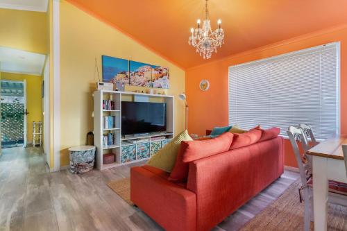 a living room with a red couch and a television at Lowood Riverelle Cottage in Lowood