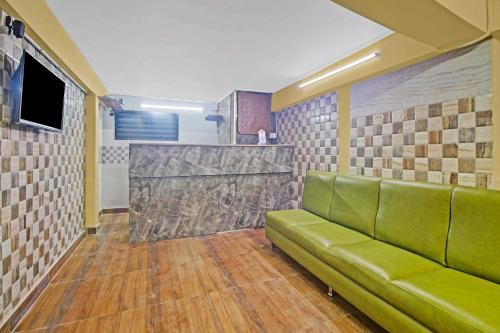a living room with a green couch and a counter at Super Collection O Hotel Aqua Villa Near Netaji Subhash Chandra Bose International Airport in Kolkata