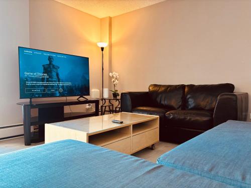 a living room with a couch and a television at 6th Floor 2 Bedroom Condo with Parking in Calgary