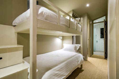 a bedroom with two bunk beds with white sheets at AL RU Farm in Sampsons Flat
