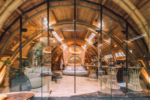 a room with a wooden ceiling and tables and chairs at Hideout Eco Bamboo House Bali in Selat