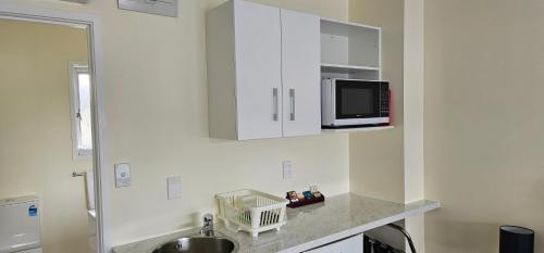 a kitchen with a sink and a microwave on the wall at Twin Coast Adventures in Kaikohe