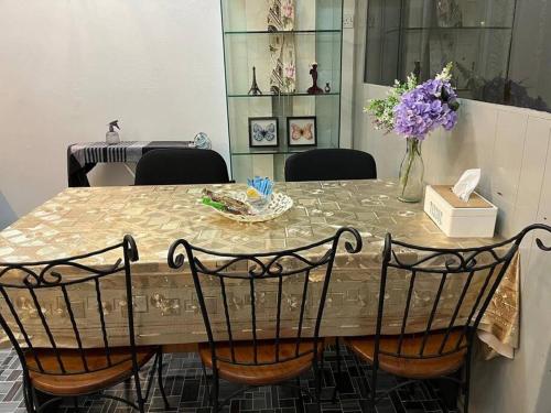 a dining room table with chairs and a vase of flowers at Near Aeon Taiping and Taiping Sentral Mall in Kamunting