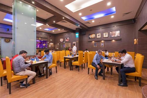 a group of people sitting at tables in a restaurant at Indismart Hotel in Kolkata