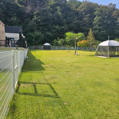 a field with a fence and a tent at Wonju Gwirae 630 Dog Pool Villa in Yongdang
