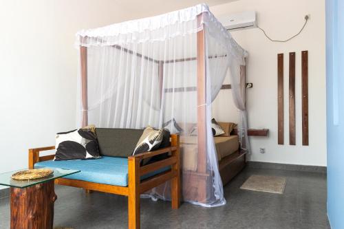a bedroom with a canopy bed and a blue chair at SriMany in Mirissa
