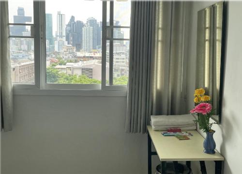 a room with a table and a window with a vase of flowers at APARTMENT A4 DINDAENG in Bangkok