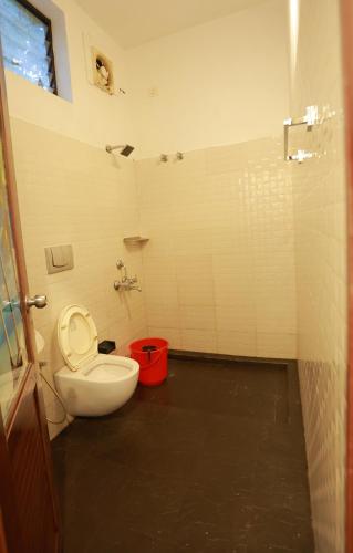 a bathroom with a toilet and a red bucket at Marari John Villa in Mararikulam
