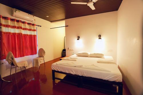 a bedroom with a bed and two chairs in it at Marari John Villa in Mararikulam